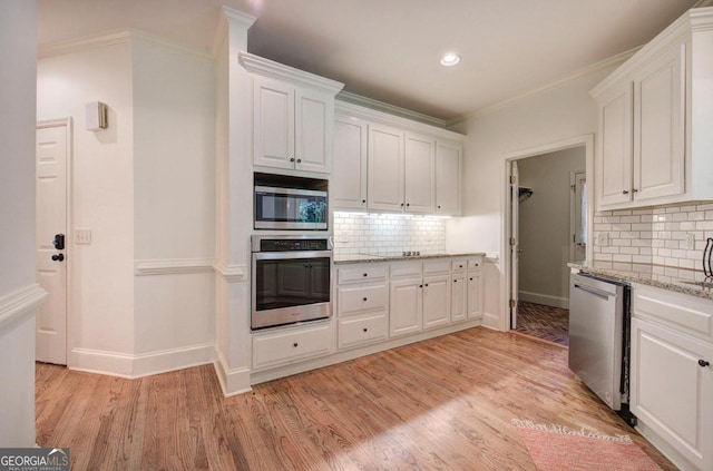 kitchen featuring white cabinets, appliances with stainless steel finishes, tasteful backsplash, and light stone countertops