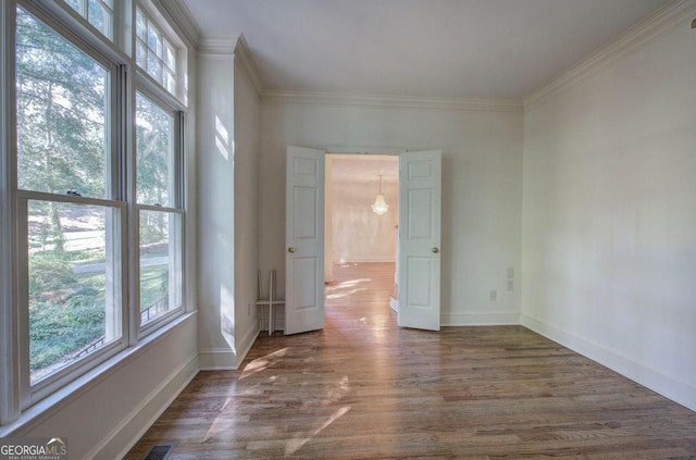 empty room featuring dark hardwood / wood-style flooring, crown molding, and a wealth of natural light