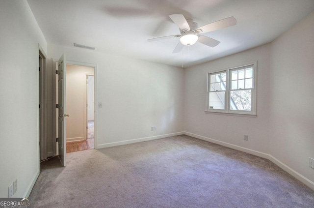 empty room with ceiling fan and light carpet