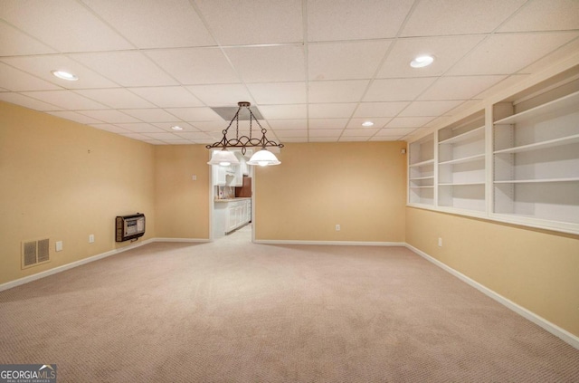 carpeted spare room featuring a paneled ceiling, heating unit, and built in features