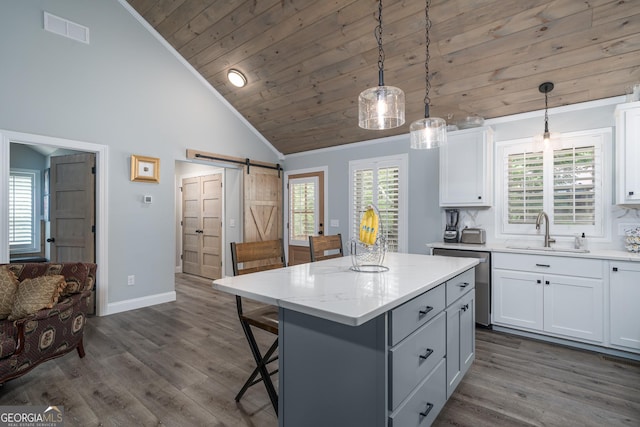 kitchen featuring decorative light fixtures, a barn door, a kitchen island, and sink