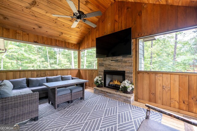 living room with wood walls, lofted ceiling, ceiling fan, a fireplace, and wood ceiling