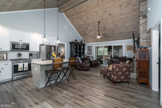 kitchen featuring white cabinetry, stainless steel appliances, tasteful backsplash, decorative light fixtures, and a kitchen island