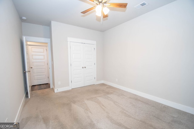 unfurnished bedroom featuring ceiling fan, a closet, and light colored carpet