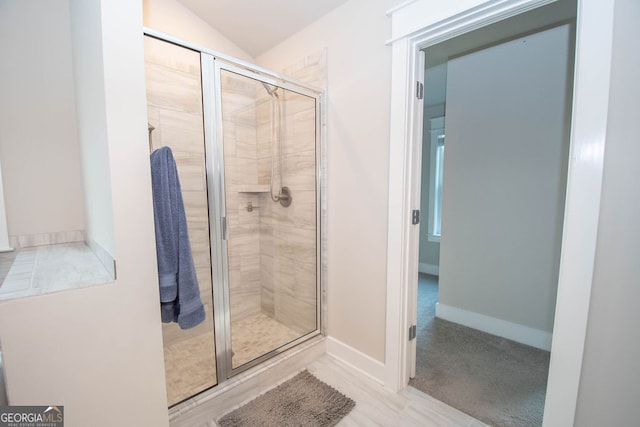 bathroom featuring a shower with shower door and lofted ceiling