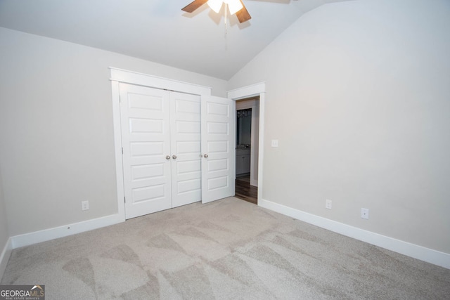 unfurnished bedroom featuring ceiling fan, a closet, light carpet, and lofted ceiling