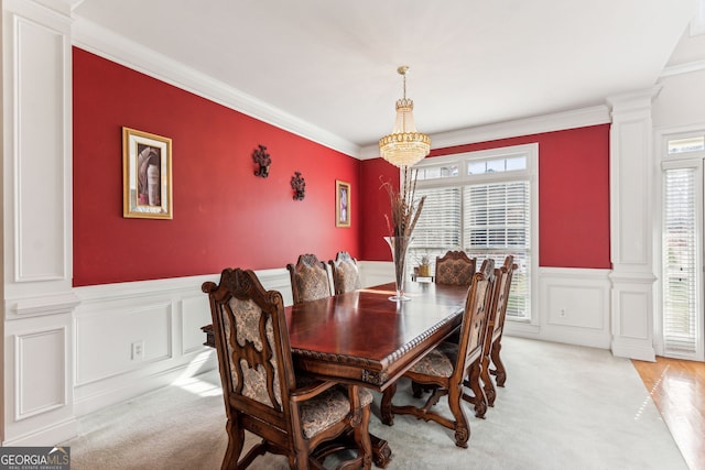 carpeted dining room with decorative columns and crown molding