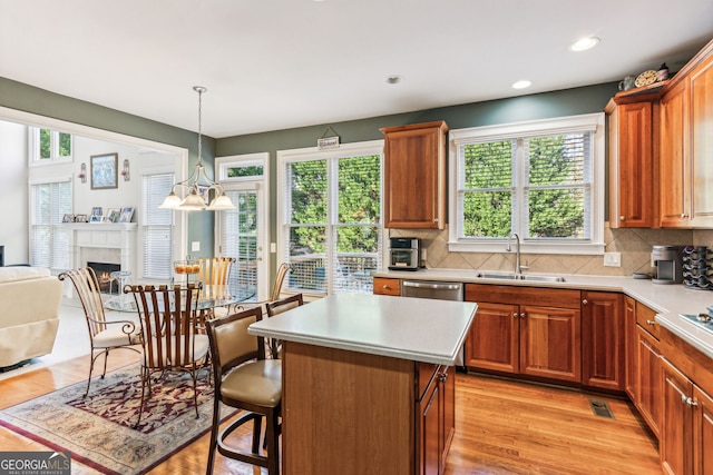 kitchen with decorative backsplash, sink, a chandelier, light hardwood / wood-style floors, and a kitchen island