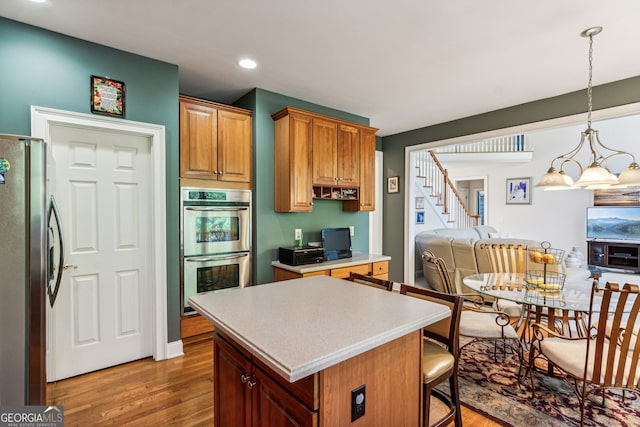 kitchen featuring appliances with stainless steel finishes, decorative light fixtures, a chandelier, dark hardwood / wood-style floors, and a kitchen island