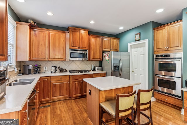 kitchen featuring sink, stainless steel appliances, a kitchen breakfast bar, a kitchen island, and light wood-type flooring