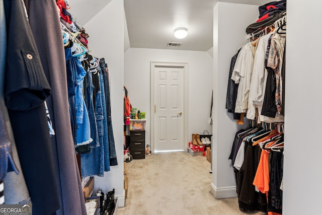 walk in closet with light carpet