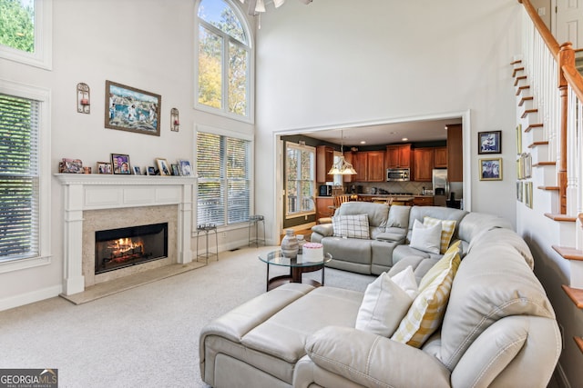 living room featuring light carpet, a fireplace, and a towering ceiling