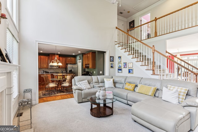 living room with crown molding, light hardwood / wood-style flooring, a towering ceiling, and a notable chandelier