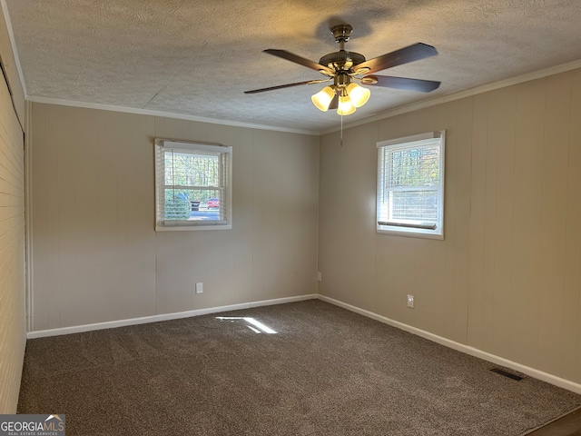 carpeted empty room featuring a textured ceiling, wooden walls, ceiling fan, and crown molding