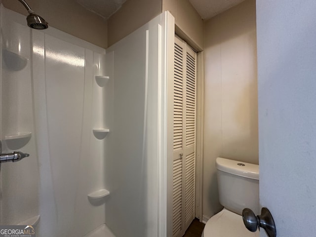 bathroom featuring a shower, a textured ceiling, and toilet