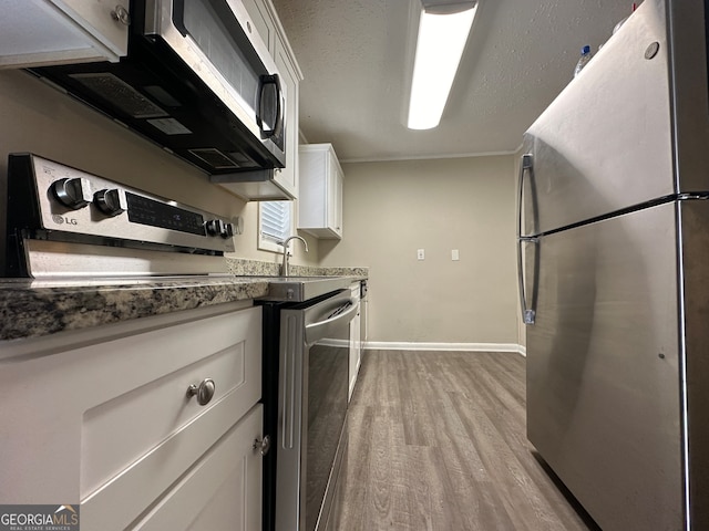 kitchen with white cabinetry, light hardwood / wood-style flooring, and stainless steel appliances