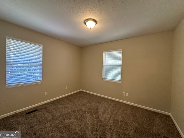 carpeted empty room featuring a textured ceiling