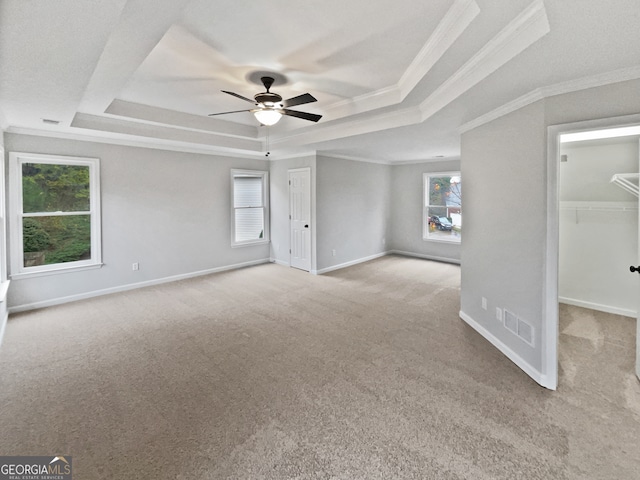 interior space featuring ceiling fan, a raised ceiling, ornamental molding, and light carpet