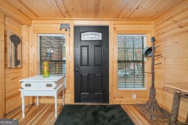 entrance foyer featuring wood-type flooring, wooden walls, and wooden ceiling