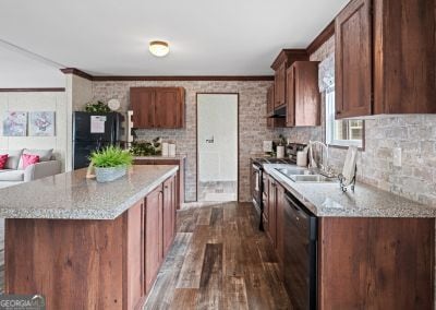 kitchen with dark hardwood / wood-style flooring, light stone counters, ornamental molding, sink, and black appliances