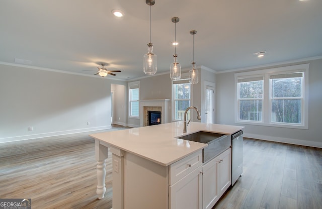 kitchen featuring white cabinetry, dishwasher, ceiling fan, crown molding, and a kitchen island with sink