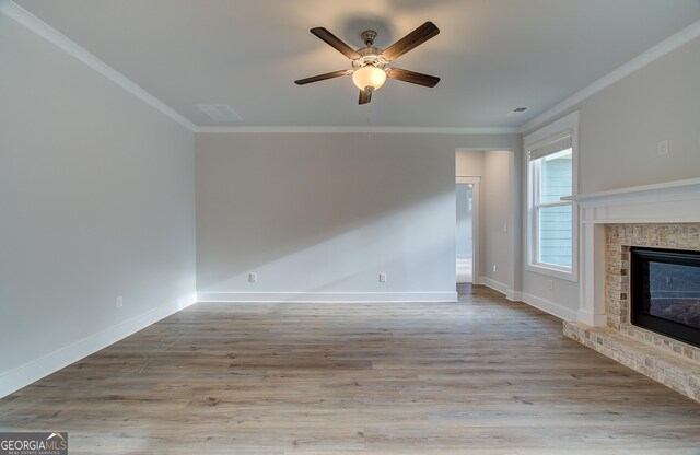 unfurnished living room with ceiling fan, light wood-type flooring, ornamental molding, and a fireplace