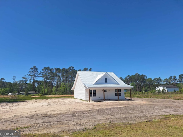 exterior space with dirt driveway and covered porch