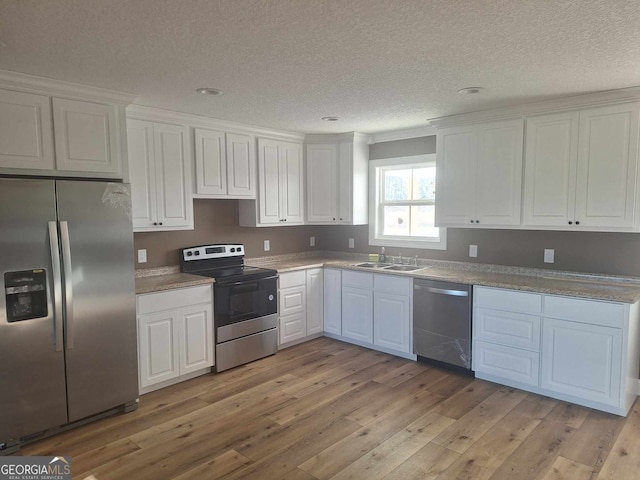 kitchen with appliances with stainless steel finishes, light hardwood / wood-style flooring, white cabinetry, and sink