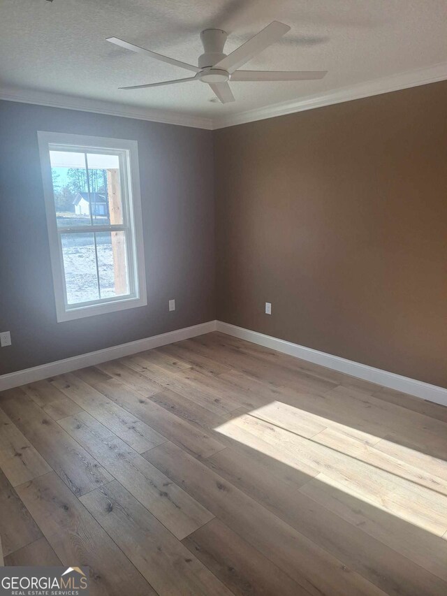 spare room featuring ceiling fan, light hardwood / wood-style flooring, a textured ceiling, and ornamental molding