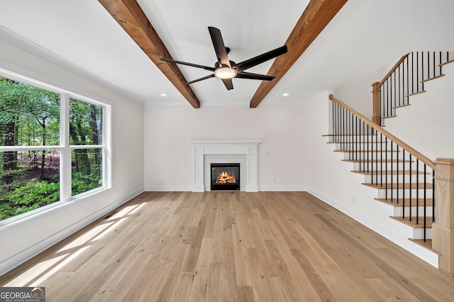 unfurnished living room with a tile fireplace, beam ceiling, light wood-type flooring, and ceiling fan