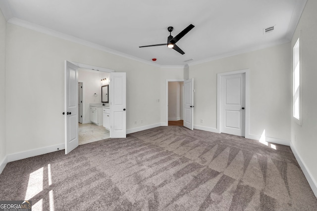 unfurnished bedroom featuring ensuite bath, ceiling fan, light colored carpet, and ornamental molding