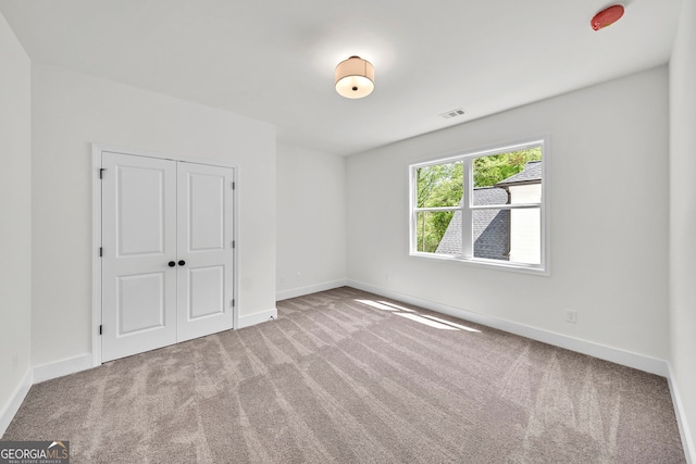 unfurnished bedroom featuring carpet, a closet, visible vents, and baseboards