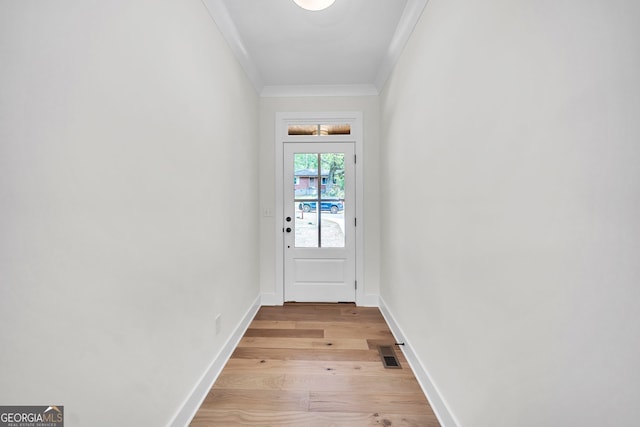 entryway with light wood-style floors, visible vents, ornamental molding, and baseboards