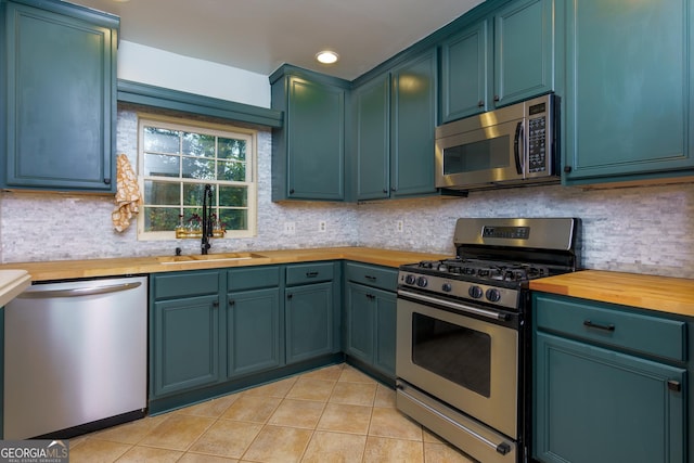 kitchen with wooden counters, sink, decorative backsplash, light tile patterned floors, and stainless steel appliances