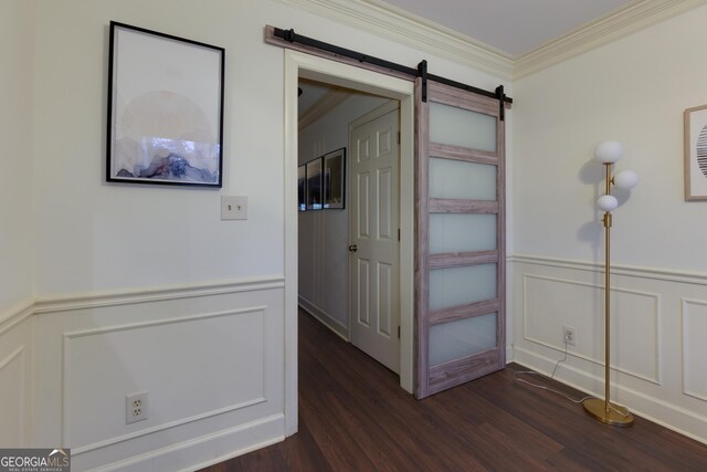 hallway featuring dark hardwood / wood-style floors, a barn door, and ornamental molding