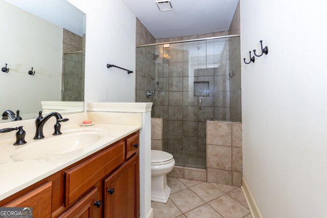 bathroom with tile patterned flooring, vanity, toilet, and a shower with door