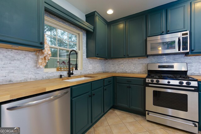 kitchen with light tile patterned flooring, stainless steel appliances, butcher block countertops, and sink