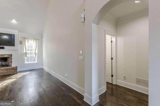 interior space with dark hardwood / wood-style floors, crown molding, and a brick fireplace