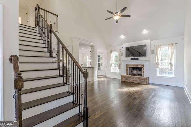 unfurnished living room with high vaulted ceiling, a brick fireplace, a wealth of natural light, and ceiling fan