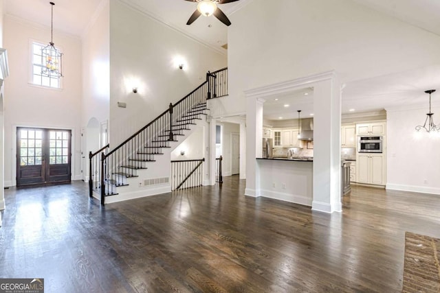 unfurnished living room with plenty of natural light, dark hardwood / wood-style flooring, and a towering ceiling