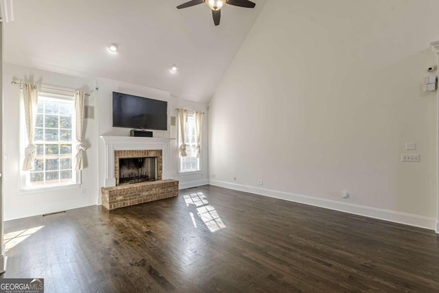 unfurnished living room featuring ceiling fan, high vaulted ceiling, dark hardwood / wood-style floors, and a brick fireplace