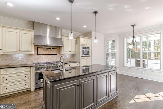 kitchen featuring cream cabinets, dark hardwood / wood-style flooring, decorative light fixtures, and wall chimney range hood