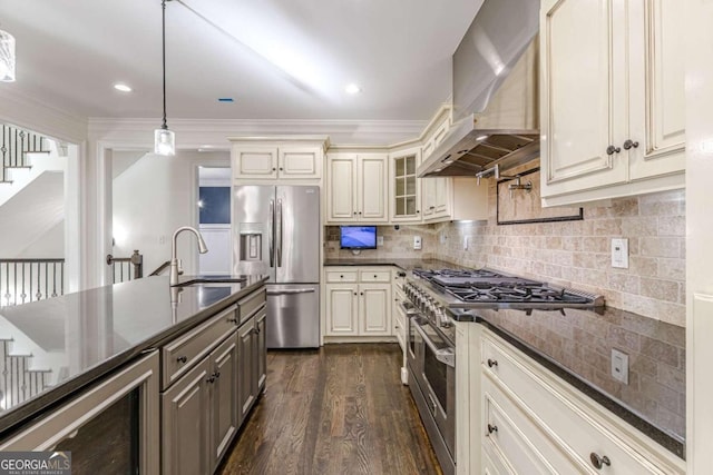 kitchen with sink, beverage cooler, wall chimney range hood, pendant lighting, and appliances with stainless steel finishes