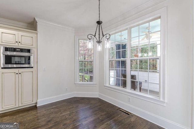 unfurnished dining area with plenty of natural light, ornamental molding, dark wood-type flooring, and ceiling fan with notable chandelier