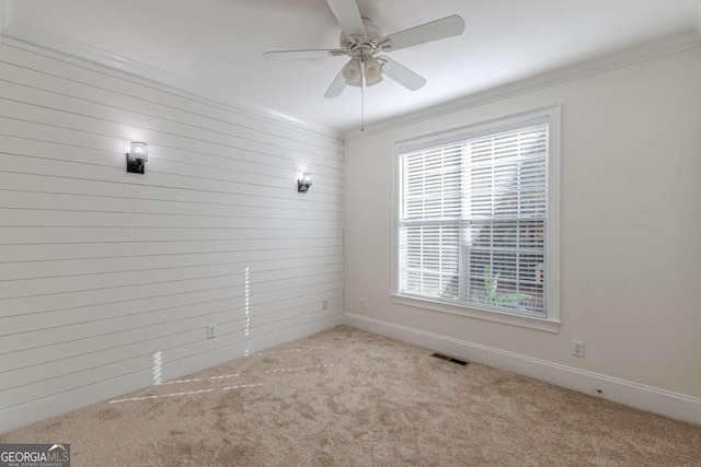 carpeted spare room featuring ceiling fan and ornamental molding