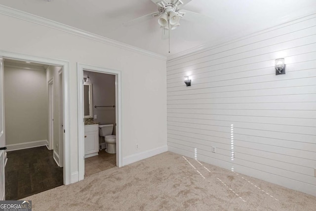 unfurnished bedroom with carpet flooring, ensuite bathroom, ceiling fan, and crown molding