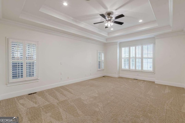 carpeted spare room with a tray ceiling, crown molding, and ceiling fan