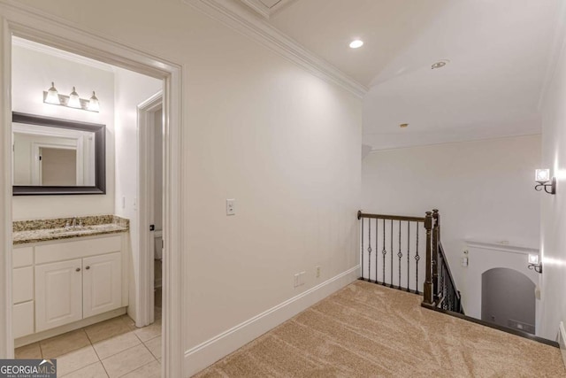 hallway with light colored carpet, ornamental molding, and sink