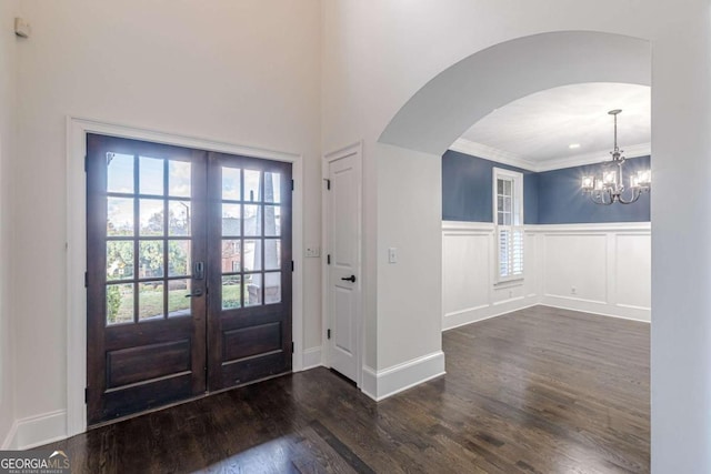 foyer entrance with crown molding, french doors, dark hardwood / wood-style floors, and an inviting chandelier