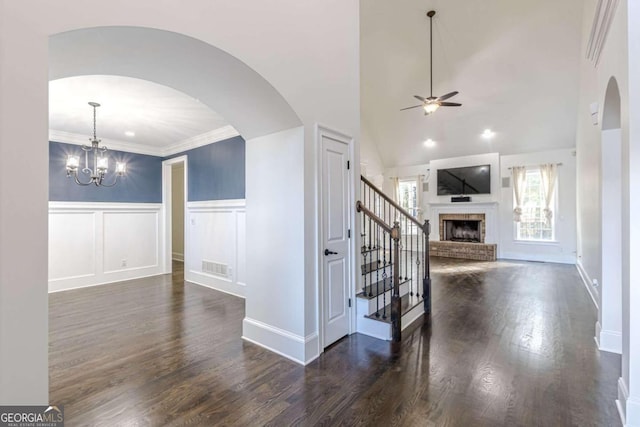 interior space with a brick fireplace, ornamental molding, ceiling fan with notable chandelier, hardwood / wood-style flooring, and high vaulted ceiling